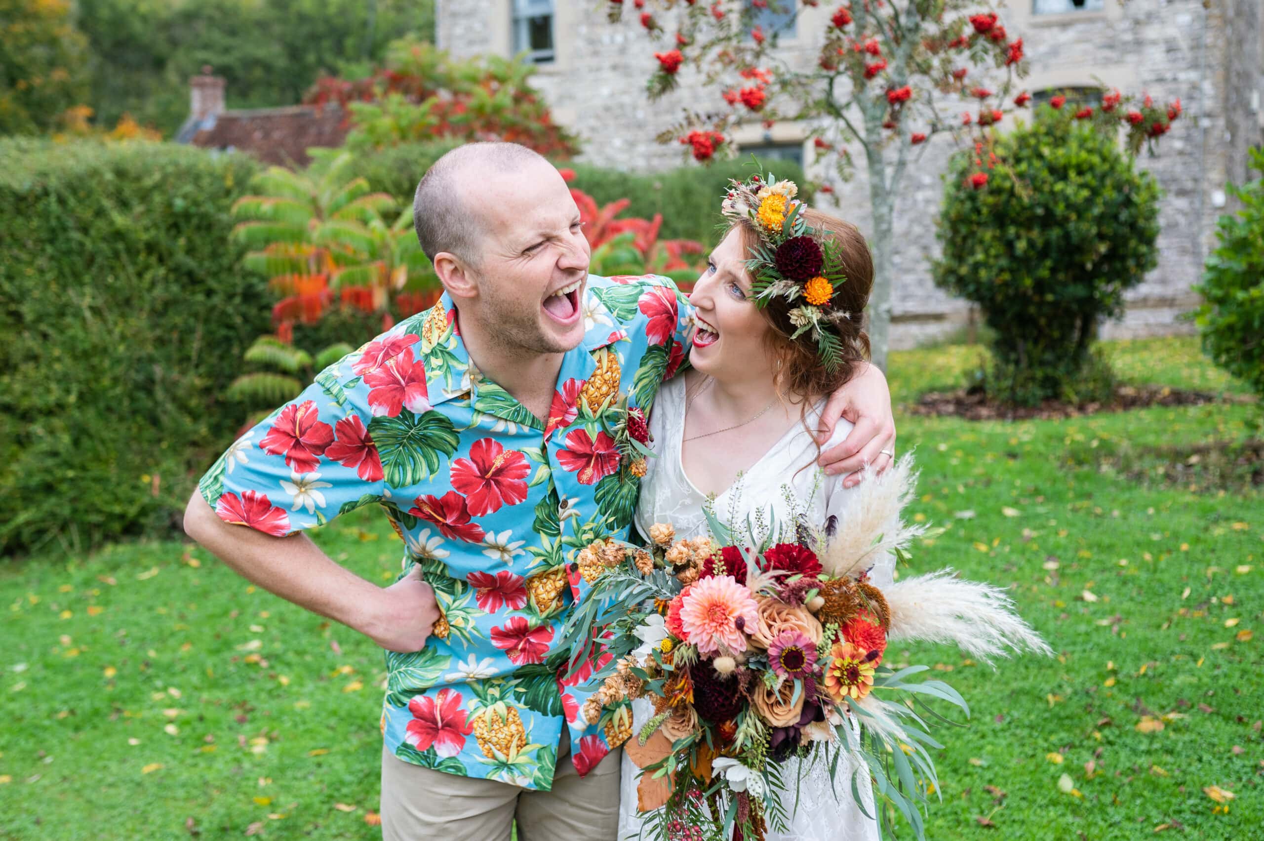 Colourfully dressed coupels laughing on their wedding day.