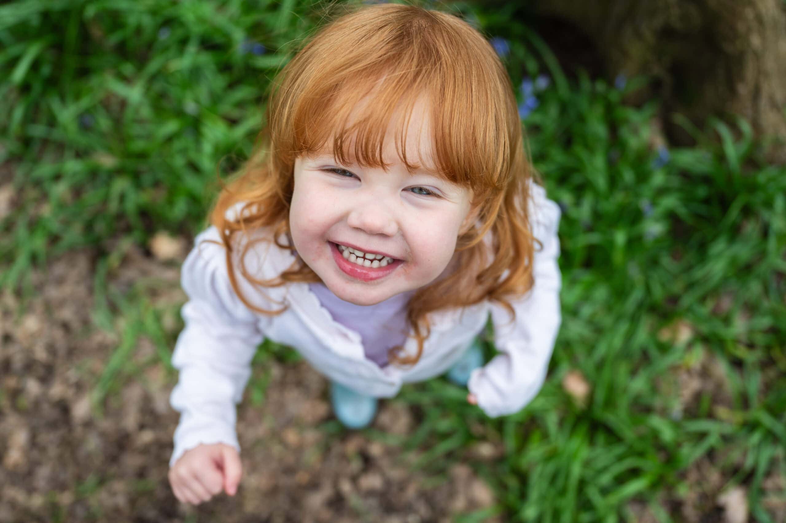 A baby with a dummy lies on a blanket looking at the camera
