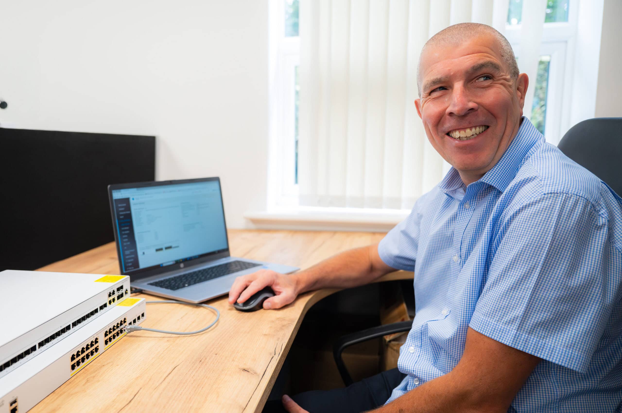 A smiling man at his desk with a laptop, business photography in Nottingham