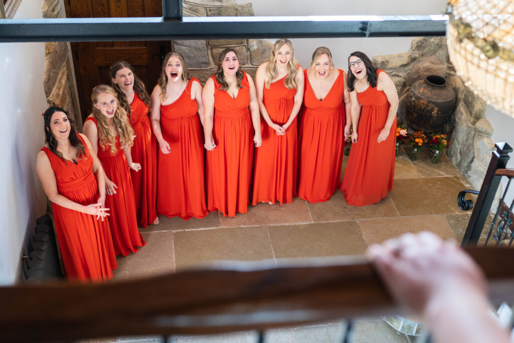 Bridesmaids in orange dresses laughing as they see the bride for the first time, Nottingham wedding photographer