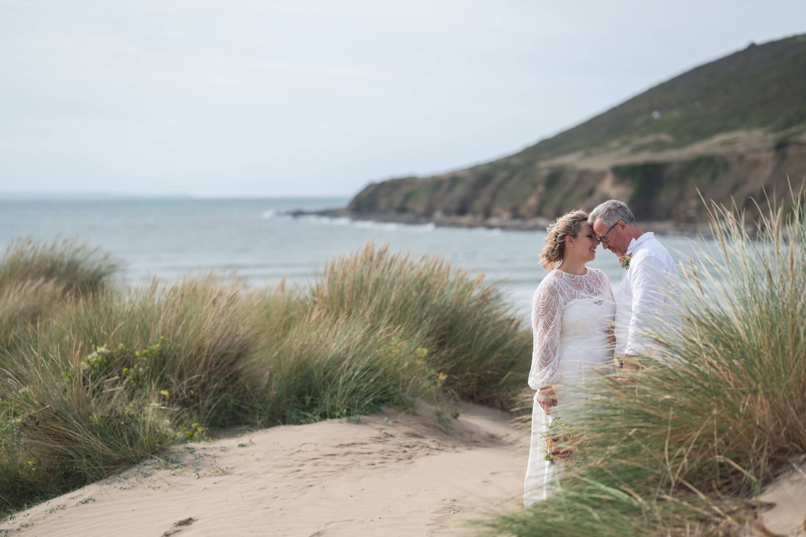 Bride and Groom share a quiet moment in the sand dunes after a beach wedding