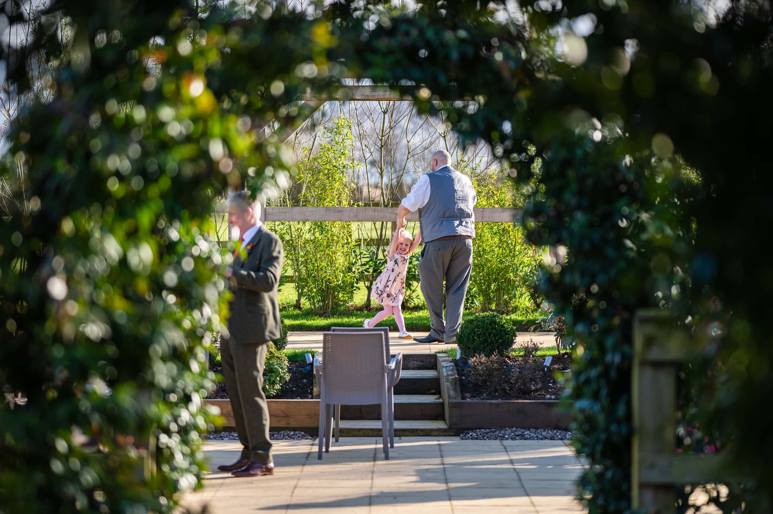 Guests mingle in the garden at Coton House Farm, framed by greenery