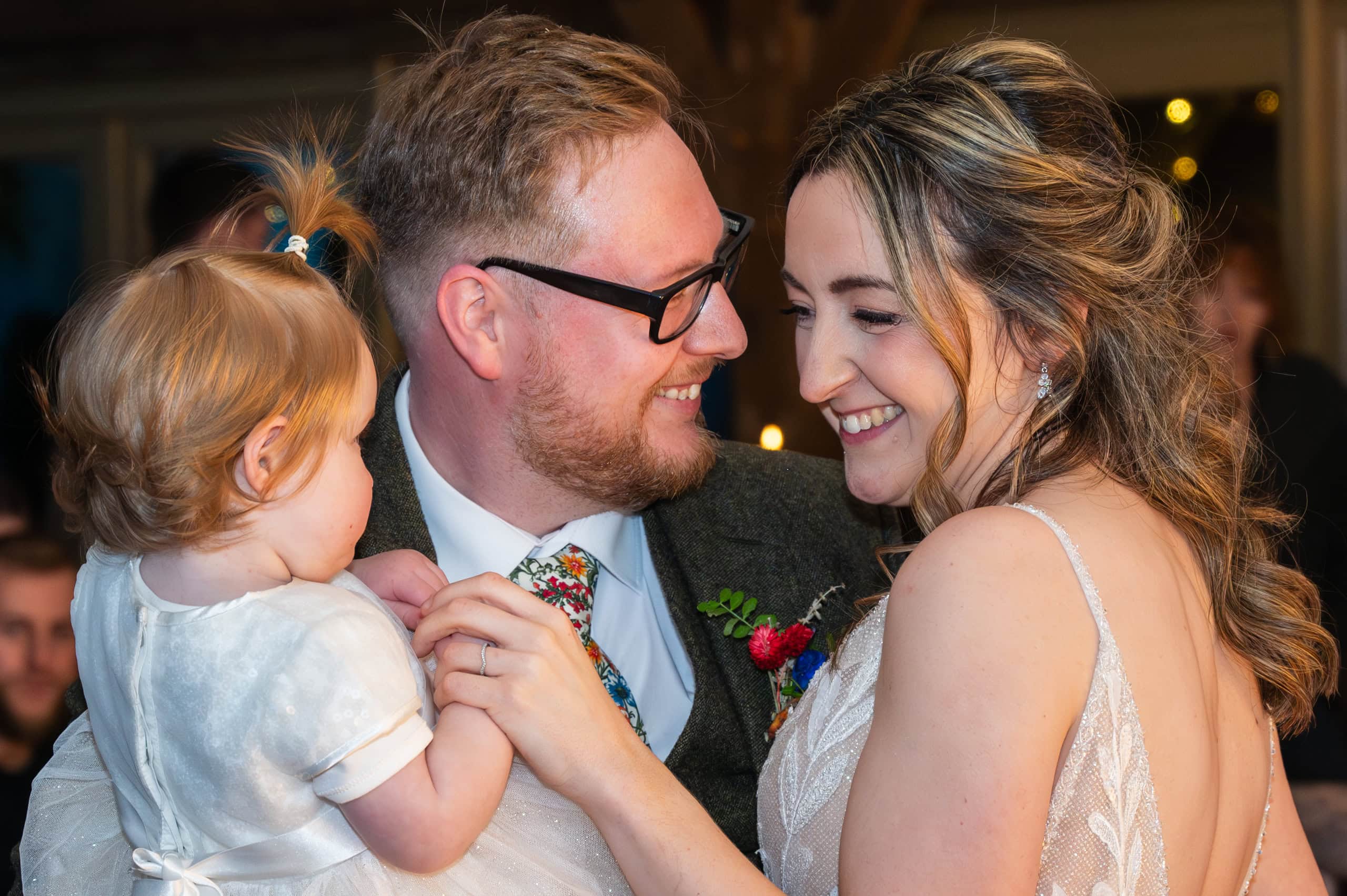 Bride and groom share a dance with a toddler at Coton House Farm