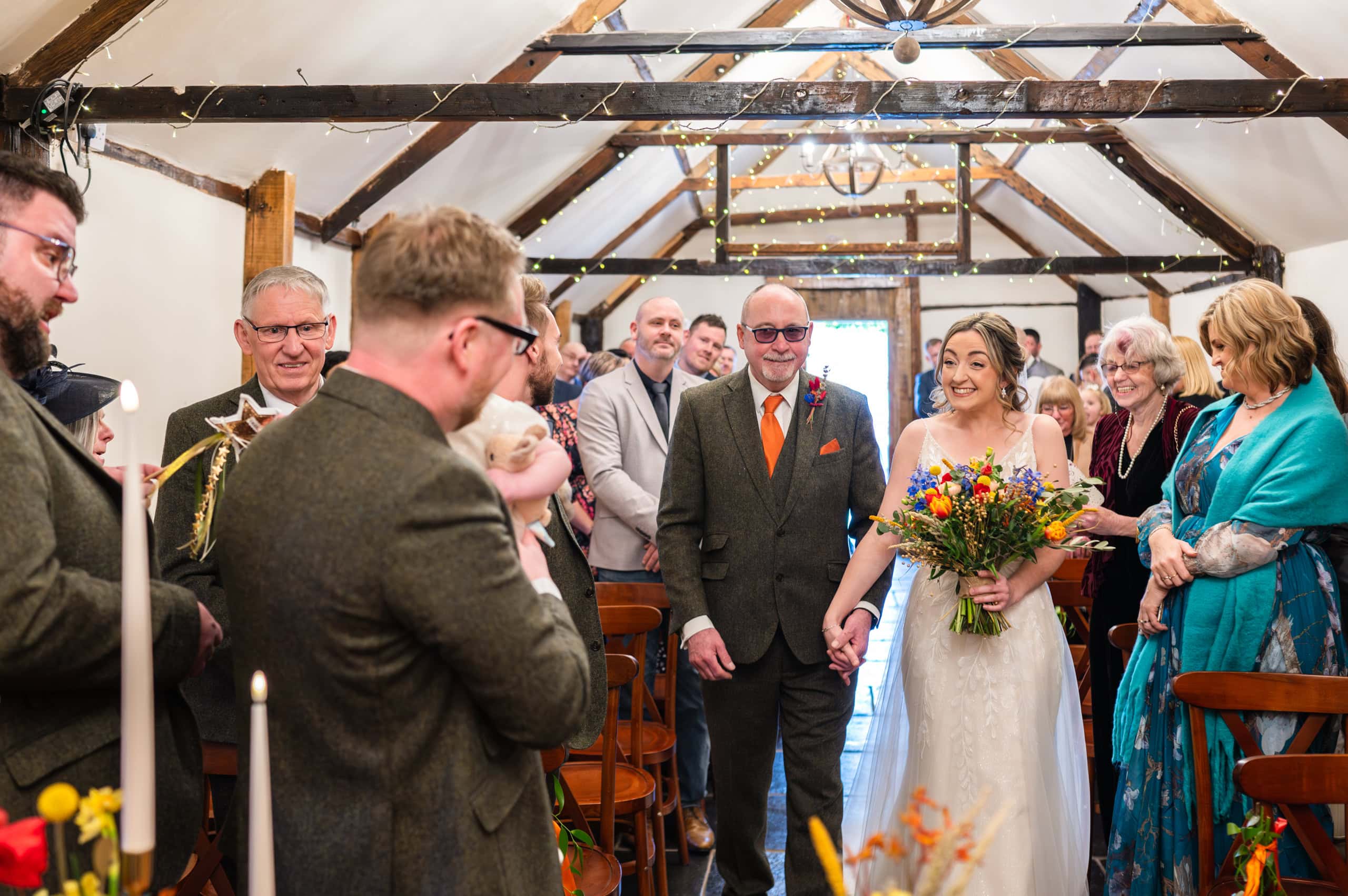Bride walks down the aisle in the ceremony barn at Coton House Farm