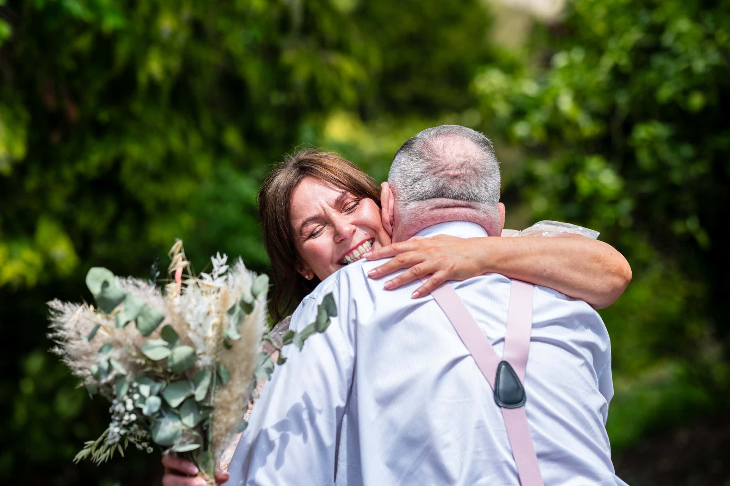 Bride hugs a guest in the gardens at Wollaton Hall