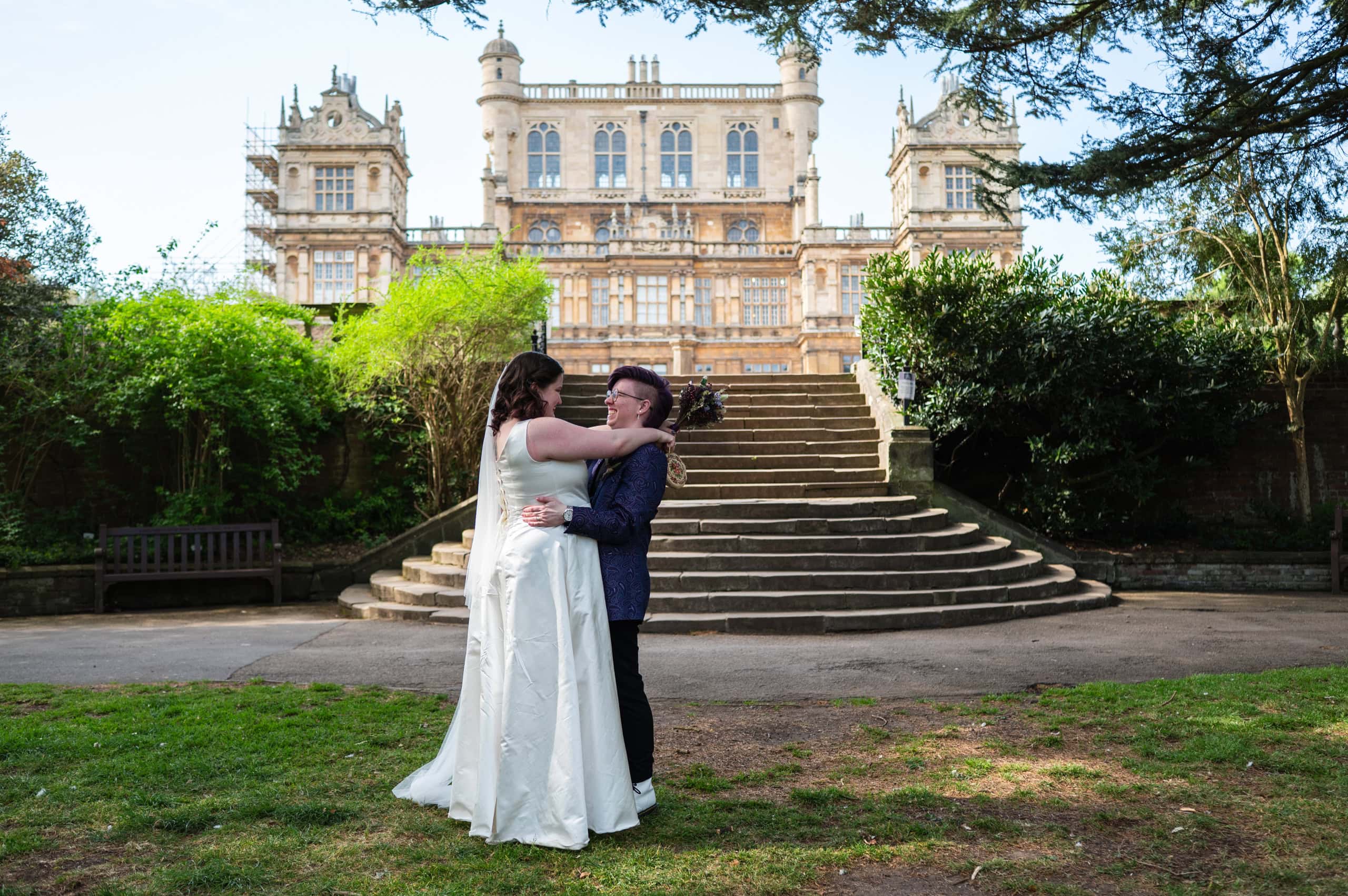The couple embrace at the foot of the steps in front of Wollaton Hall