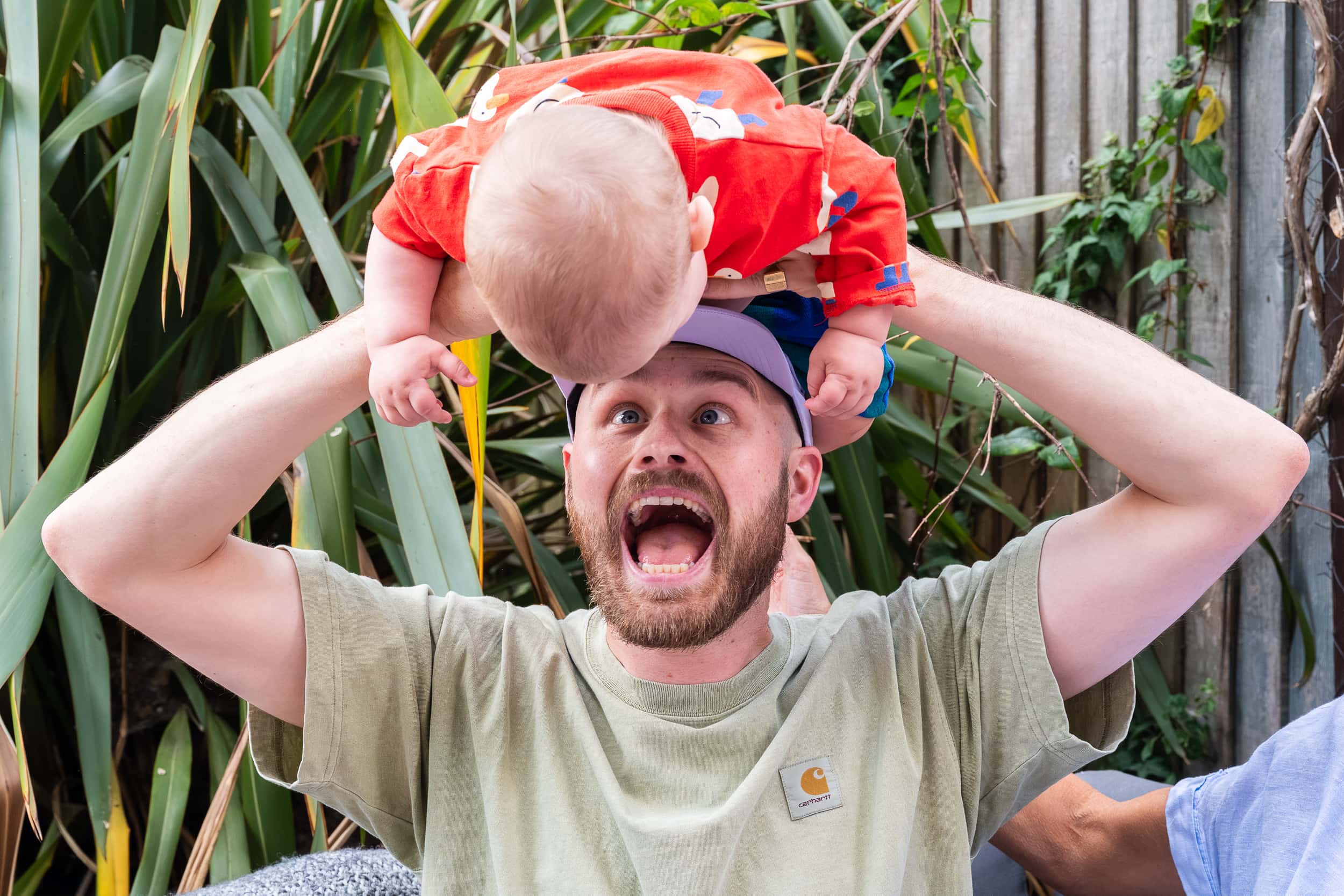 Dad pulls a funny face as he holds his baby on his head