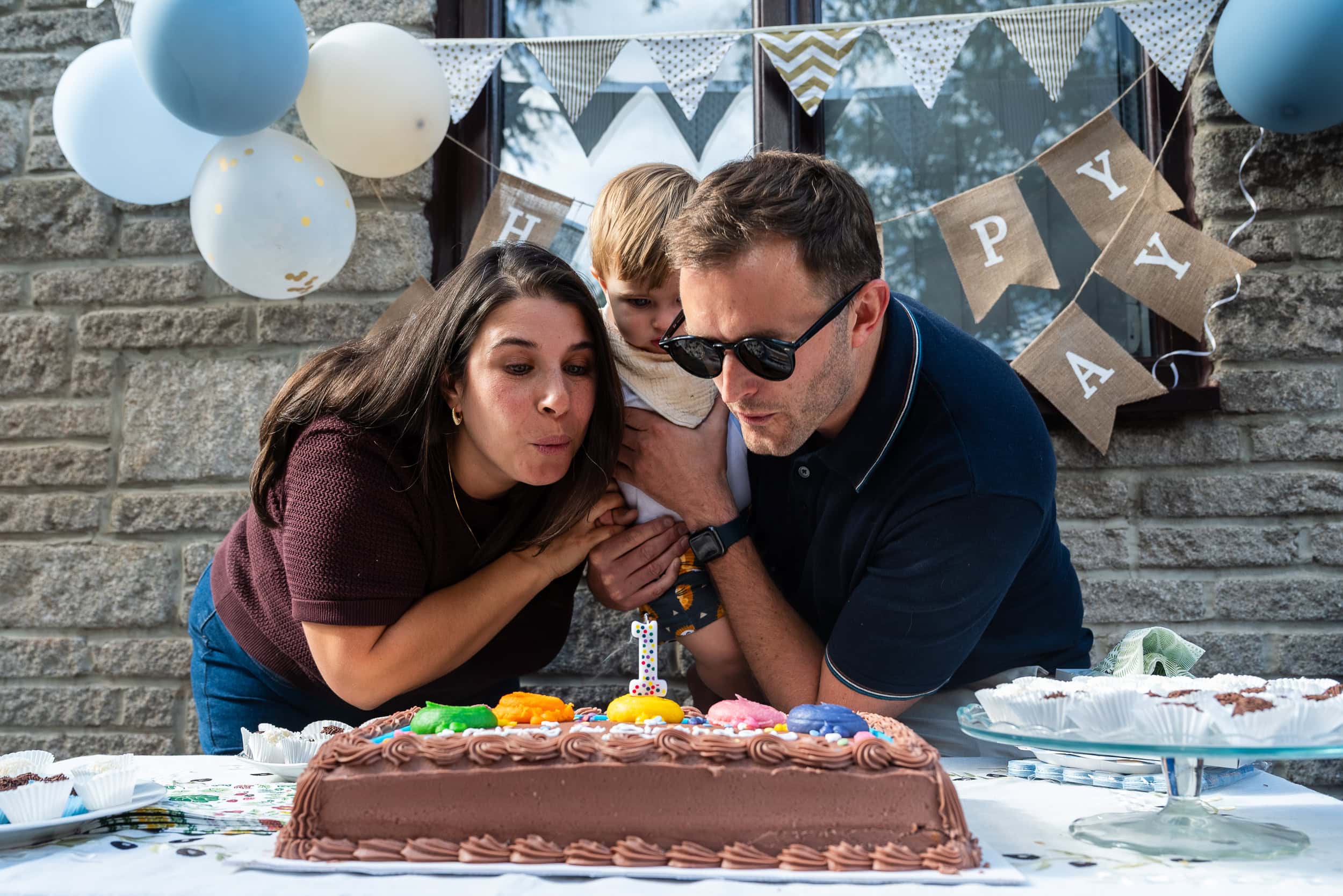 Parents blow out the candles on a birthday cake at a family party