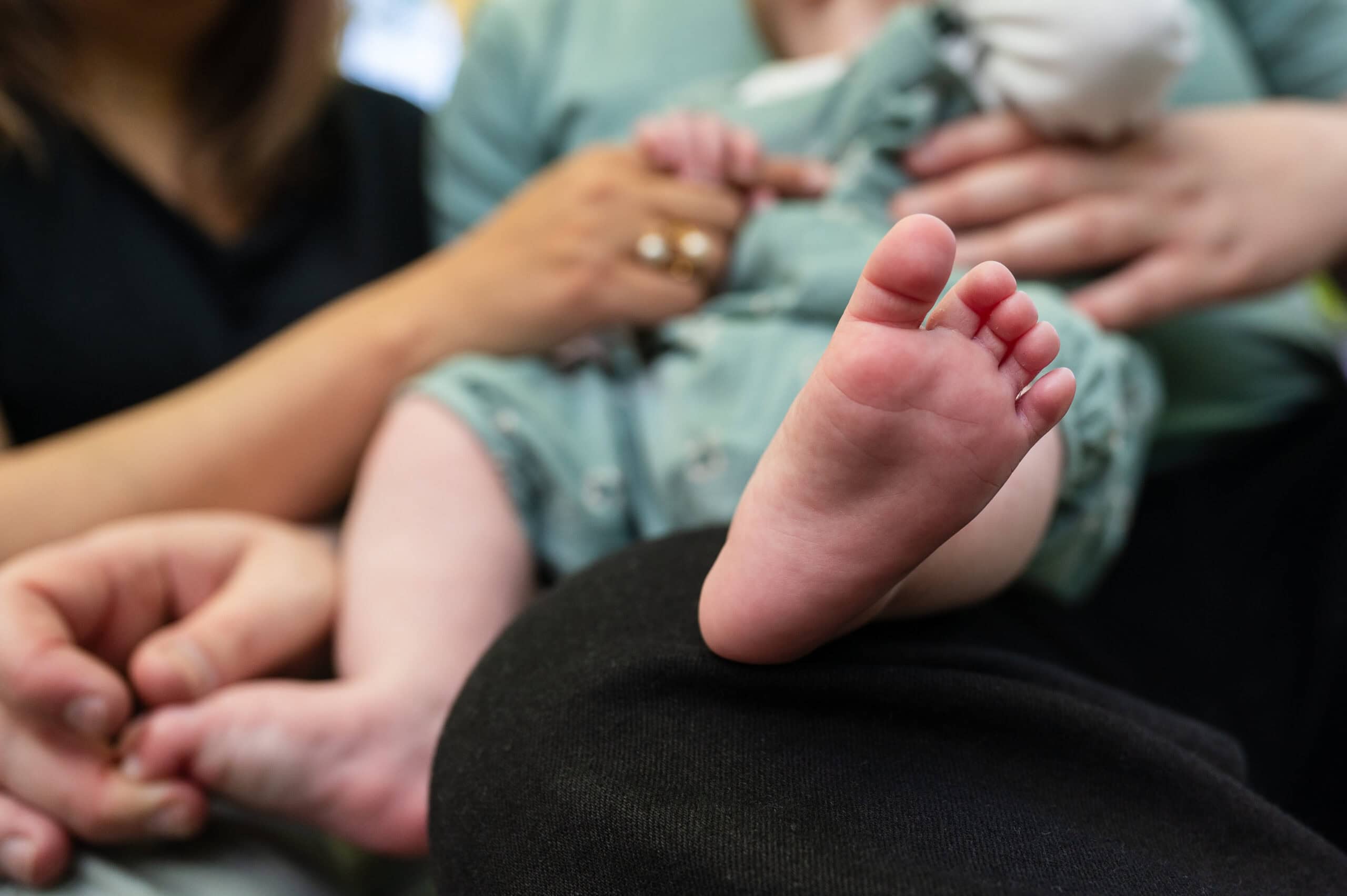 Close-up of a baby's foot as the baby sits on a parent's lap