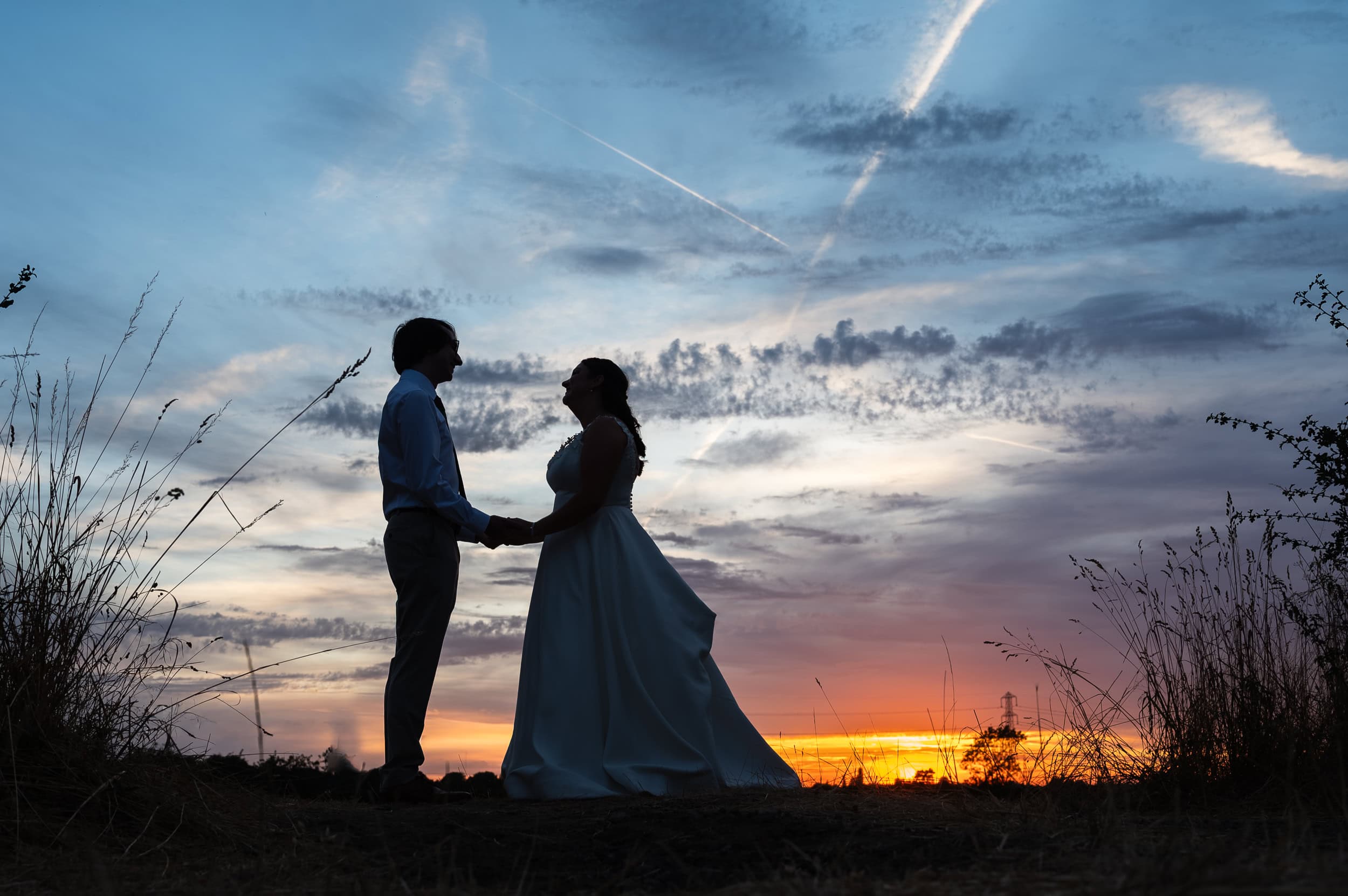 Bride and groom at sunset in the field behind Dunstall Barn