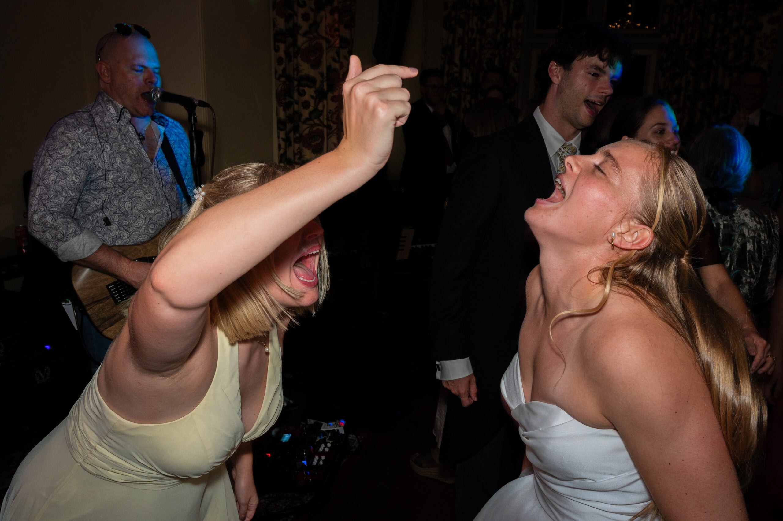 The bride and a bridesmaid dancing wildly in front of the band at a Holme Pierrepont Hall wedding.