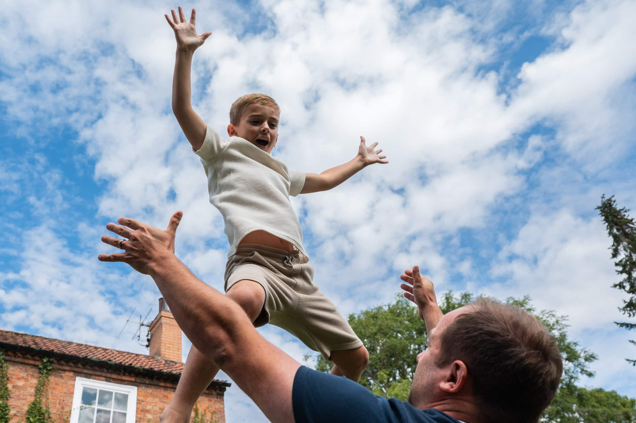 Dad throws his son high into the air at a family gathering