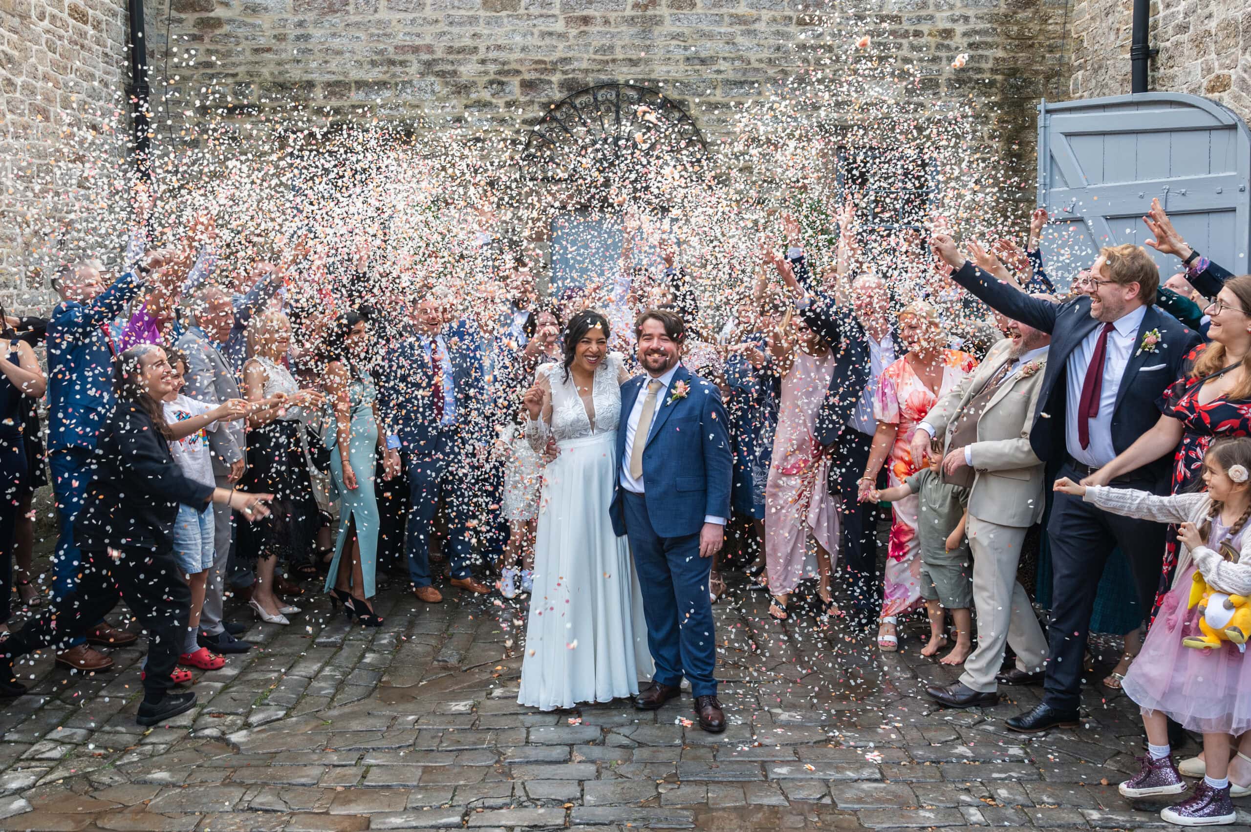 Bride and groom walk through a shower of confetti from their guests at Pennard House, Nottingham wedding photographer