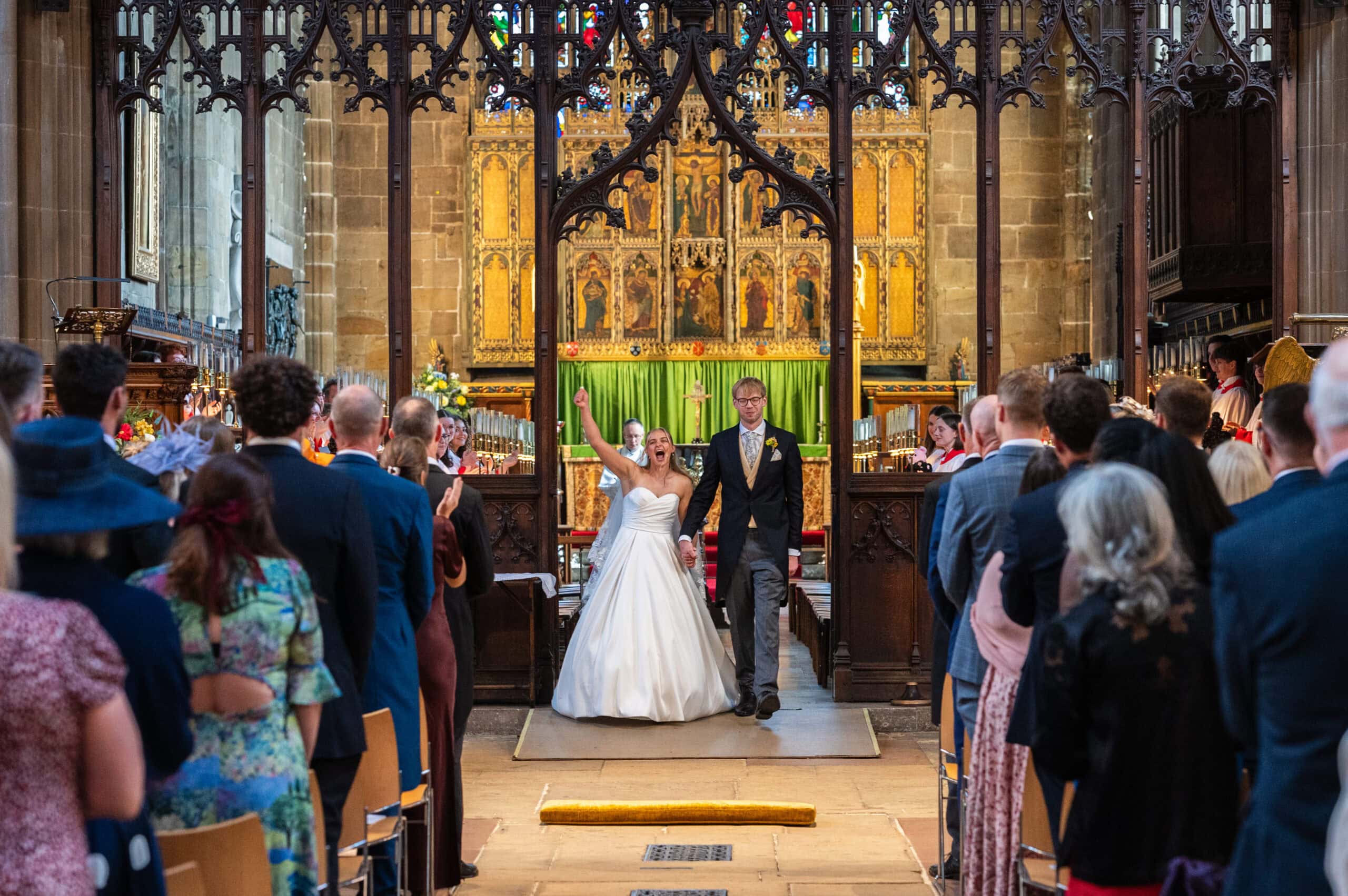 A bride raising her arm in celebration as the couple turn to walk back down the aisle at St Mary's, Nottingham.