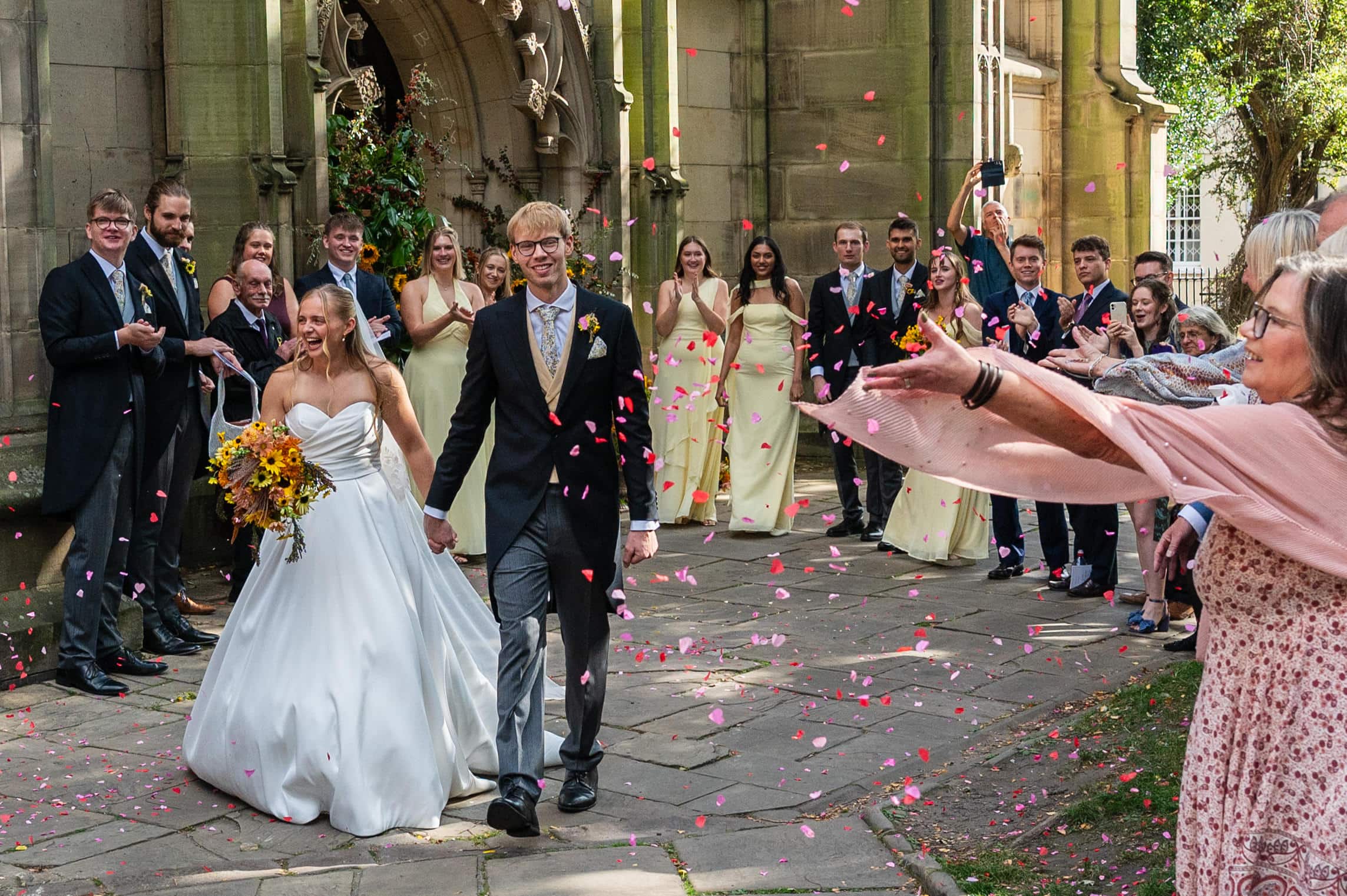 Guests throwing pink petal confetti as the newlyweds leave St Mary's in the Lace Market.