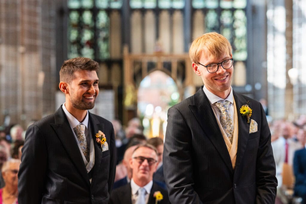 The groom and best man smiling as they wait at the front of St Mary's in the Lace Market before a wedding.
