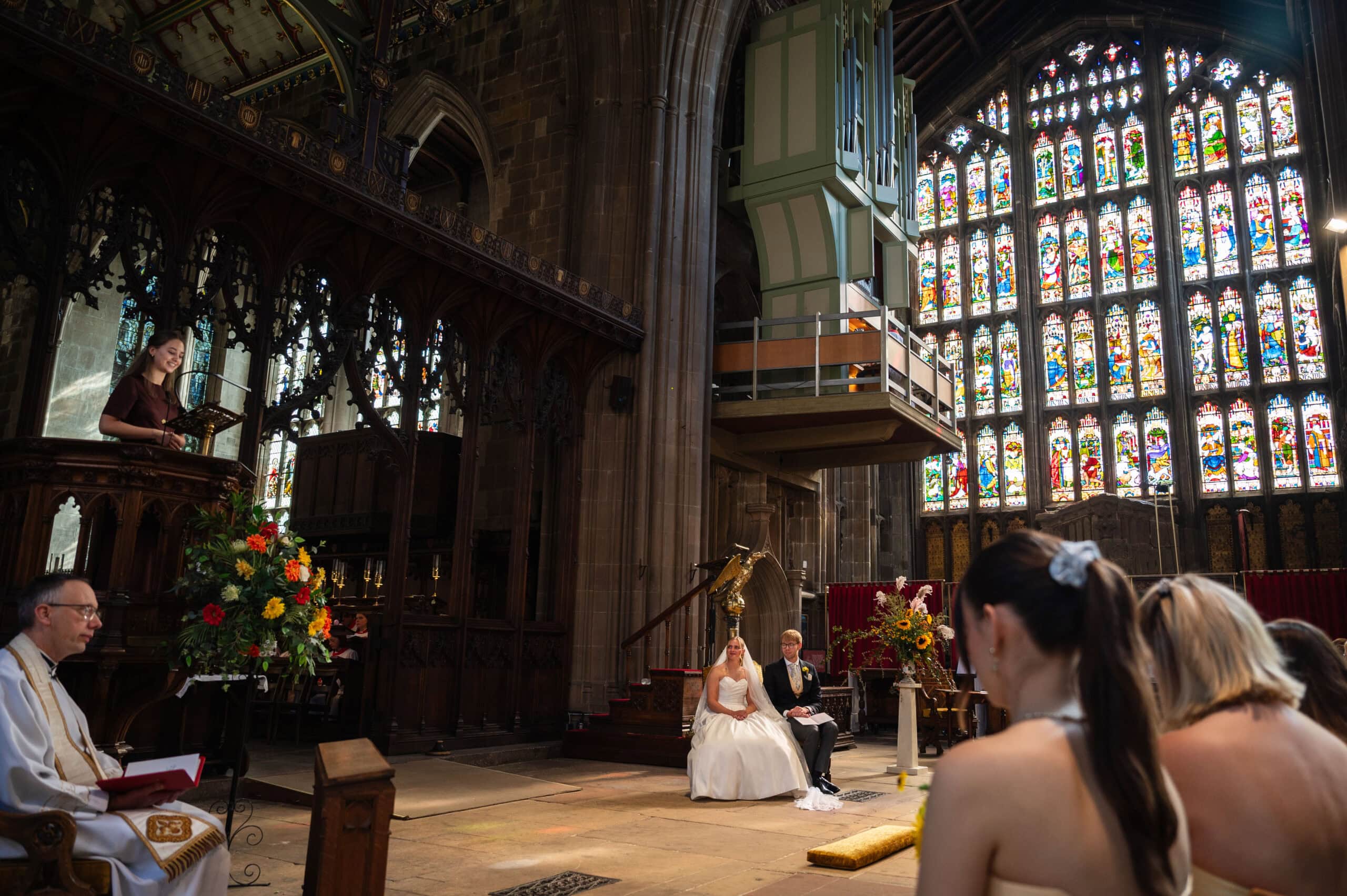 A wedding ceremony at St Mary's church in Nottingham, with the church's tall stained glass windows behind the couple.