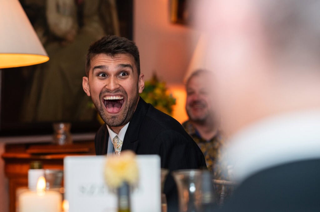 A wedding guest laughing open-mouthed during the speeches.