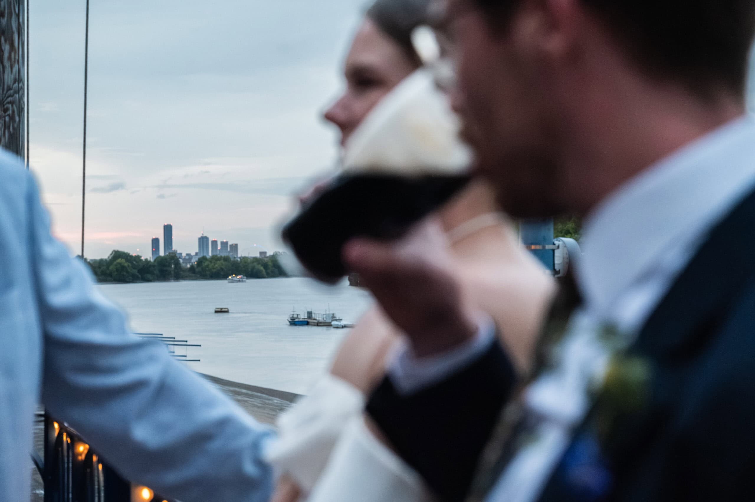 Wedding guests with drinks on the balcony overlooking the River Thames at London Rowing Club
