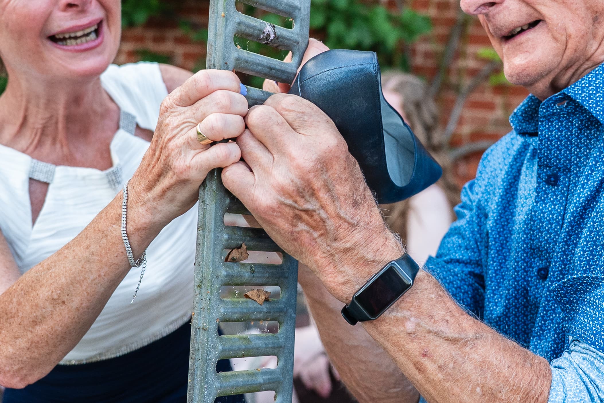 Two wedding guests laughing as they lean on a step ladder in the garden