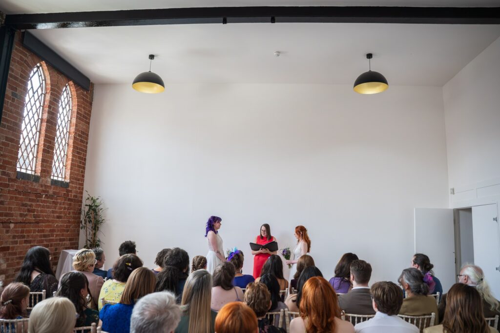 Guests watching a celebrant ceremony in the white-walled warehouse room at Fazeley Studios, Birmingham