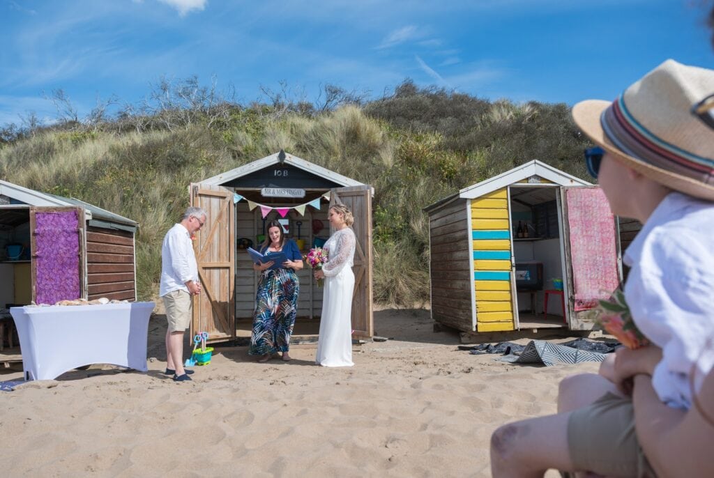 Celebrant from Gem of a Wedding leading Lizzy and Richard's ceremony in front of beach huts at Saunton Sands