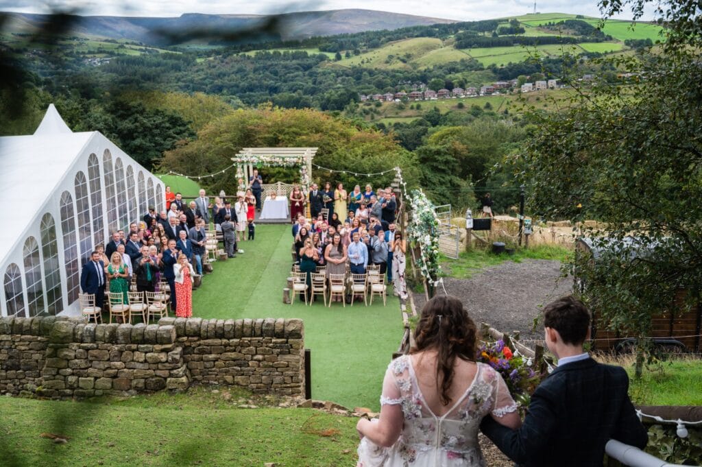 Leila walking down the outdoor aisle towards Steve at The Stables Wedding Farm, Oldham