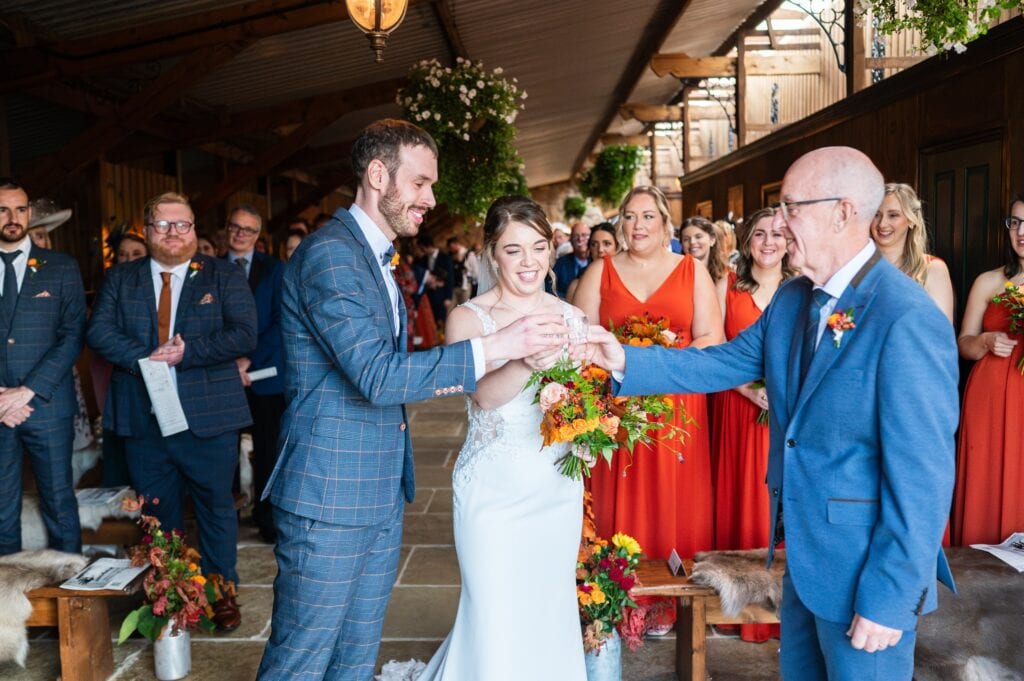 Evie's dad handing out tequila shots to Evie and Tom at the end of the aisle at Willow Marsh Farm